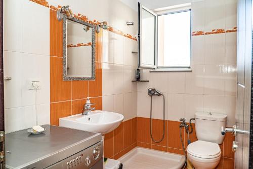 a bathroom with a sink and a toilet and a mirror at Esmeralda Apartaments in Sarandë