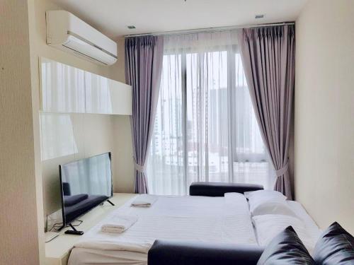 Un dormitorio con una cama grande y un televisor. en The Astra Condo by Ping, en Chiang Mai