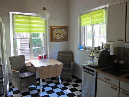 a kitchen with a table and chairs and windows at Rossis Haus in Schneverdingen