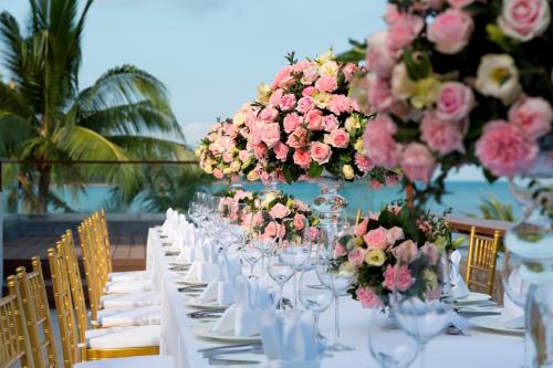 a long table with vases filled with pink flowers at Anantara Lawana Koh Samui Resort in Chaweng