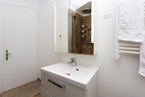 une salle de bain blanche avec un lavabo et un miroir dans l'établissement La Saleina Apartment - Chamonix All Year, à Chamonix-Mont-Blanc
