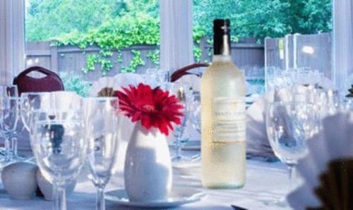 a table with a bottle of wine and glasses at Hickstead Hotel in Bolney