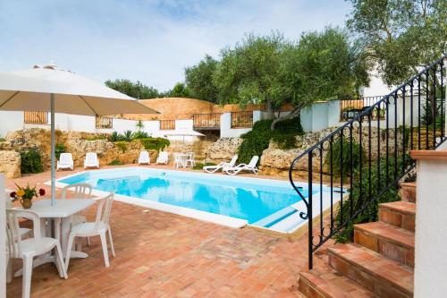 a swimming pool with a table and an umbrella at Case Di Latomie in Castelvetrano Selinunte