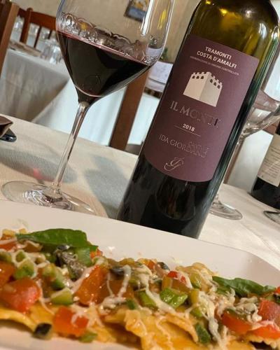 a plate of pizza next to a bottle of wine at Il Raduno in Tramonti