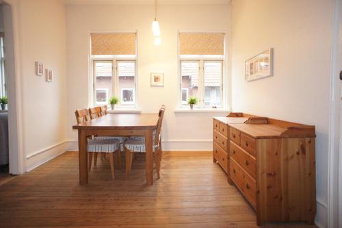 a dining room with a table and chairs and windows at id. 061. Jyllandsgade in Esbjerg