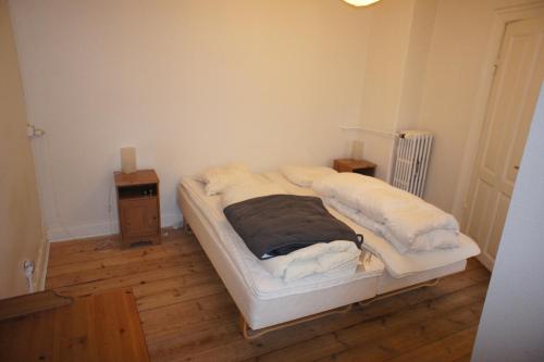 ein weißes Bett in einem Zimmer mit Holzboden in der Unterkunft id. 061. Jyllandsgade in Esbjerg