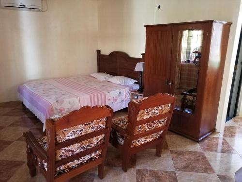 a bedroom with a bed and two chairs at Mauristudio in Bel Ombre