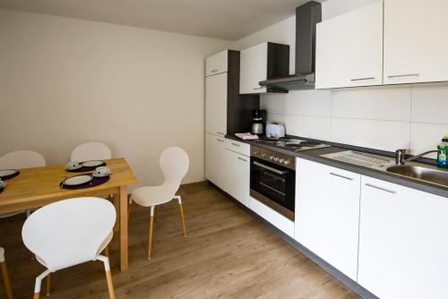a kitchen with white cabinets and a wooden table and chairs at Monteurwohnung 2 Zimmer in Havekost