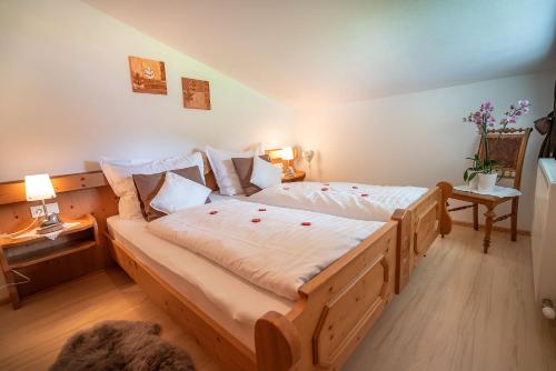 Un dormitorio con una gran cama de madera con sábanas blancas. en Landhaus Bellamontes, en Leutasch