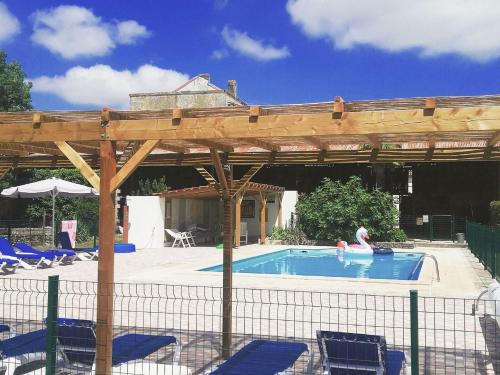 a wooden pergola over a swimming pool with people in it at Domaine de Chantageasse in Asnières-la-Giraud