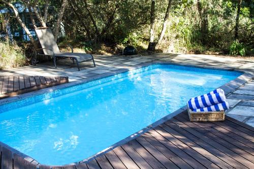a swimming pool with a deck and a chair next to it at Tsitsikhaya Lodge in Stormsrivier