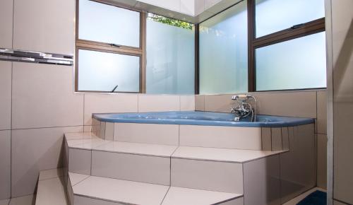 a bathroom with a blue sink and two windows at Tsitsikhaya Lodge in Stormsrivier