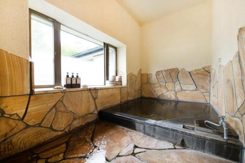 a bathroom with a bath tub with a window at 'Imi Ola House in Yufuin