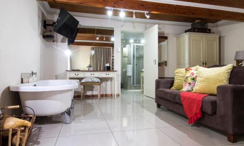 La salle de bains est pourvue d'une baignoire, d'un canapé et d'un lavabo. dans l'établissement Tsitsikhaya Lodge, à Stormsrivier
