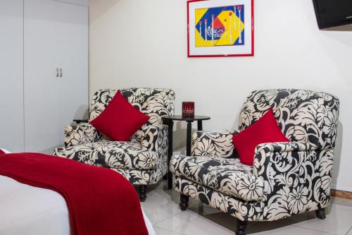 a living room with two chairs with red pillows at Tsitsikhaya Lodge in Stormsrivier