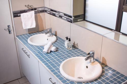 a bathroom with two sinks on a blue tiled counter at Tsitsikhaya Lodge in Stormsrivier