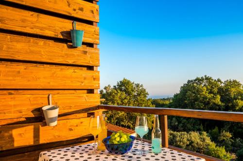 a table with wine glasses and a bowl of fruit on a deck at Le Petit in Čilipi