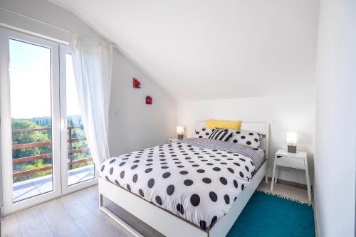 a white bedroom with a bed and a large window at Le Petit in Čilipi