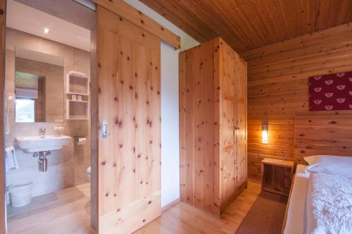 a bathroom with a wooden wall with a shower and a sink at Haus Kaunergrat in Kaunertal