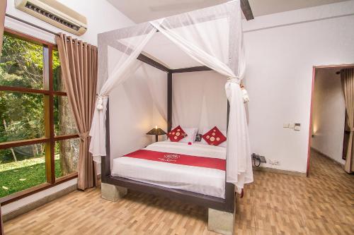 een slaapkamer met een hemelbed met rode kussens bij Puri Saron Hotel Madangan - Gianyar in Gianyar