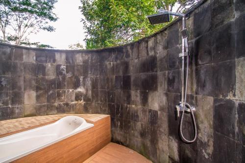 a bathroom with a bath tub and a shower at Puri Saron Hotel Madangan - Gianyar in Gianyar