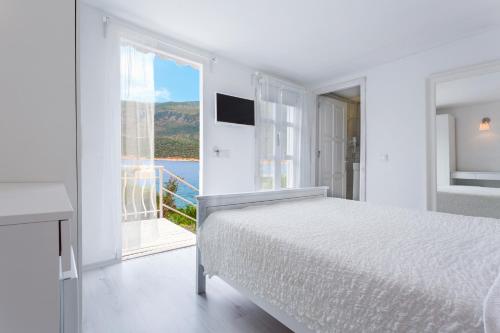 a white bedroom with a bed and a large window at Club Çapa Hotel in Kas
