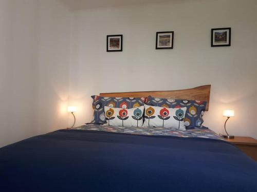 a bedroom with a blue bed with two lamps at The Cabin at No 45 in Ballater