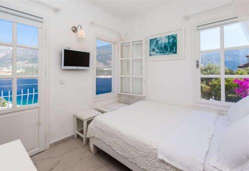 a white bedroom with a bed and two windows at Club Çapa Hotel in Kas