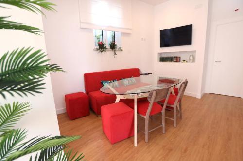 a living room with a table and red chairs at Glass Boutique - Rooms & Suites in Marinha Grande