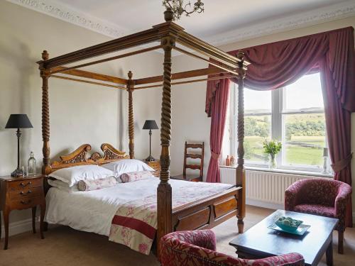 1 dormitorio con 1 cama con dosel y 2 sillas en Tennant Arms Hotel en Grassington