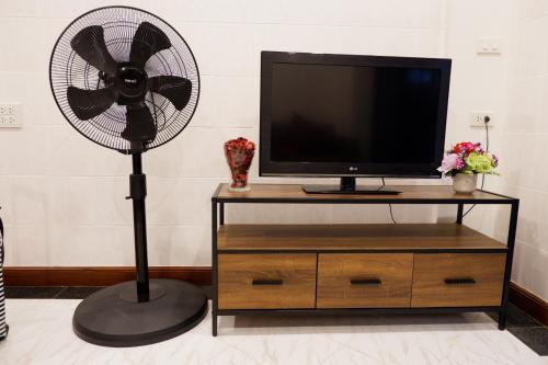 a fan sitting next to a tv and a dresser at Lisa'House in Bangkok