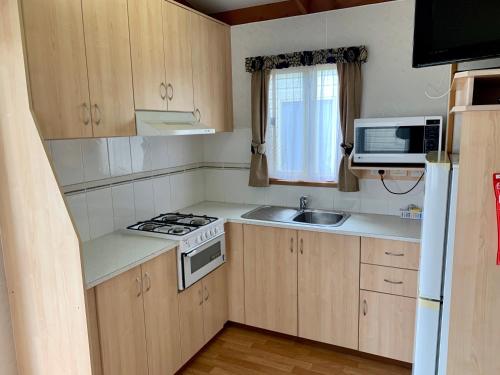 a small kitchen with a stove and a microwave at Tatura Cabin & Caravan Park in Tatura