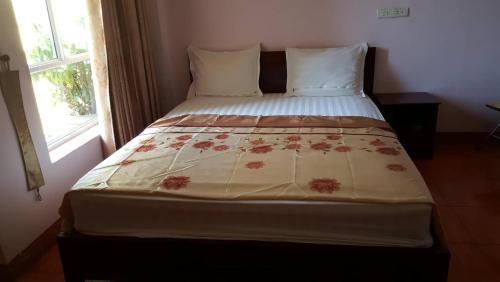 a bedroom with a bed with a floweridered blanket on it at Hai Duong Guesthouse in Hòa Bình