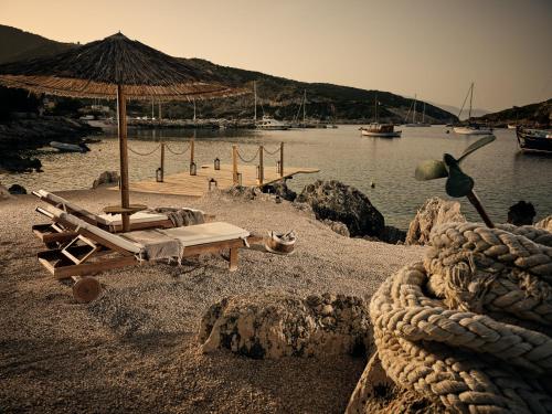 a beach with chairs and an umbrella and the water at Nobelos Seaside Lodge in Agios Nikolaos