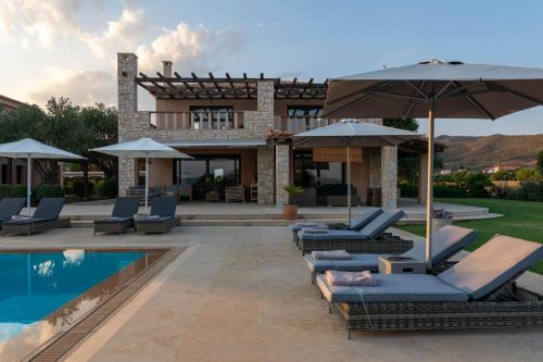 a pool with chairs and umbrellas next to a house at Therme Sea Luxury Lodge in Thermisia