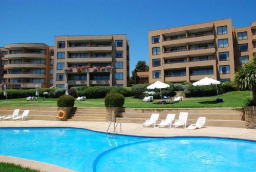 a swimming pool in front of two apartment buildings at Departamentos Mednav Mantagua in Concón