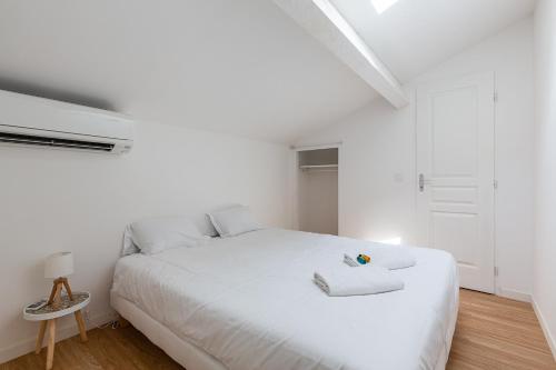 - une chambre blanche avec un grand lit blanc et une serviette dans l'établissement Le Grand Bleu- Superbe Maison avec Terrasse vue sur Mer, à Marseille