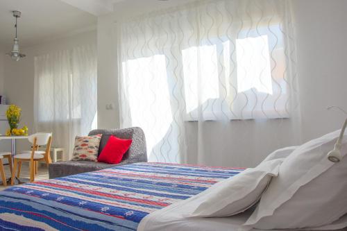 a bedroom with a bed and a chair and a window at Apartment Villa Franci in Pag