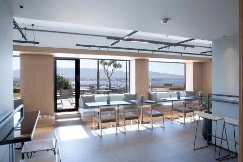 a dining room with tables and chairs and windows at The Alex Monte Kastella, Santikos Collection in Piraeus