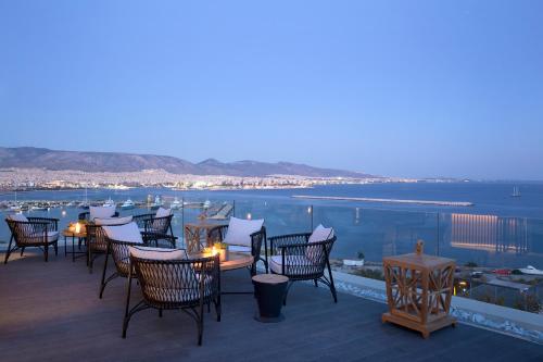 a group of chairs and tables on a deck overlooking the water at The Alex Monte Kastella, Santikos Collection in Piraeus