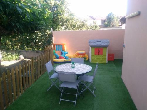 een patio met een tafel en stoelen en een speelhuis bij Appartement 62 m2 1er etage avec jardin au rdc in Saint-Génis