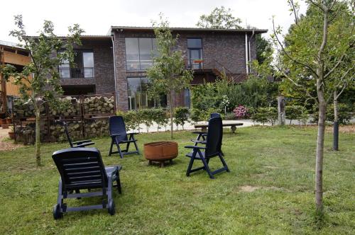 a group of chairs sitting in the grass in front of a building at Gästewohnung Hardinghaus am Teich in Warendorf