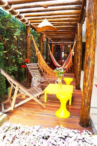 a deck with a hammock and a table and a bench at Pousada Baobá e SPA in Olinda
