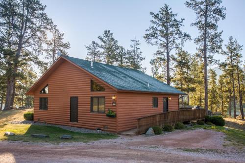 a log cabin in the woods with a fence at Lodge at Palmer Gulch in Hill City