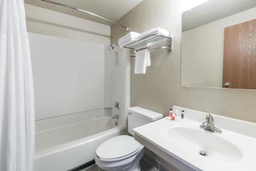 a bathroom with a white toilet and a sink at Super 8 by Wyndham Devils Lake in Devils Lake