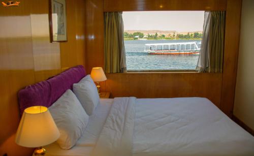 a bedroom with a bed and a window with a boat in the water at GTS Nile Cruise Luxor Aswan every monday from Luxor friday from Aswan in Luxor