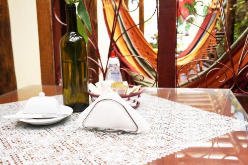 a glass table with a bottle of wine and a napkin at Pousada Baobá e SPA in Olinda