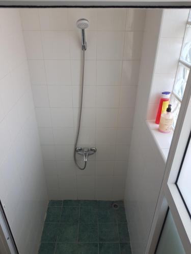 a shower in a white tiled bathroom at TRIANON Hostel - Central Paphos Old Town in Paphos City