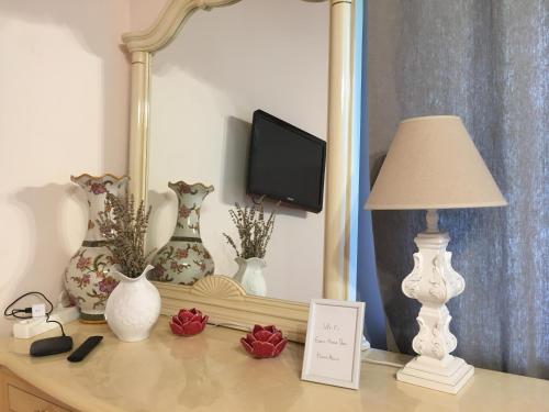 una mesa con jarrones, una lámpara y un espejo en Dana Guest House, en Roja