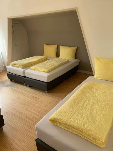 two beds with yellow pillows in a room at Wein Lodge Durbach - Gruppenhaus Weingut Neveu in Durbach